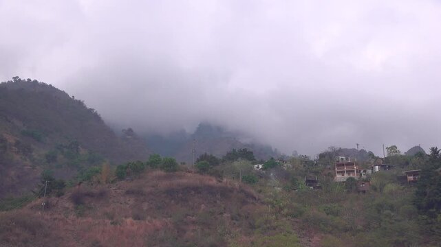 Low angle view of houses on a mountain in Guatemala with clouds rolling in
