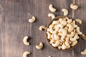 Organic roasted cashew nuts in a wooden bowl. Top view. 
