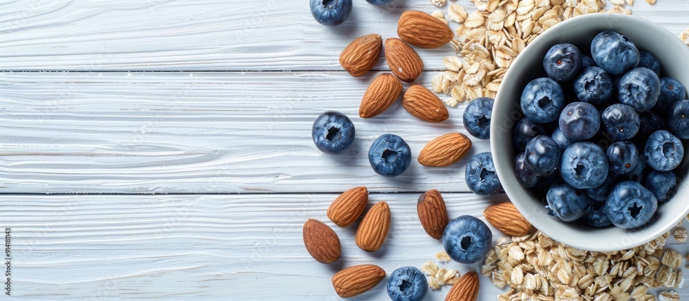 Poster top view of a white wooden background with a breakfast oatmeal featuring blueberries and almonds pro
