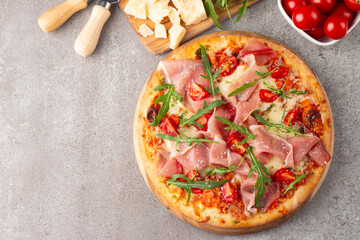 Pizza with prosciutto, ham, arugula, spinach, tomatoes, pesto, cheese and parmesan. Italian cuisine