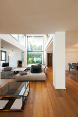 Modern living room with large sofa, with chaise longue, central coffee table, above a large carpet. Interior of a modern house on two levels
