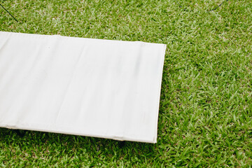 White camping bed or cot for camping or travel on green grass background. Copy space.