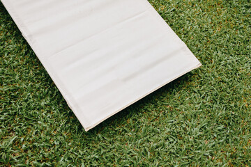 White camping bed or cot for camping or travel on green grass background. Copy space.