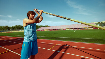 Pole vaulter demonstrating strength and motivation during training, young man standing at outdoor...
