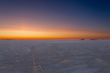 Sunset behind island within frozen sea
