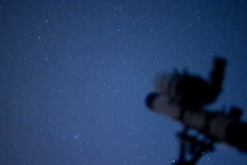 A telescope points towards a star-filled night sky offering a glimpse into the vastness of space.
