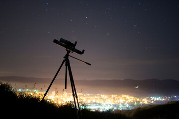 A telescope points towards a star-filled night sky offering a glimpse into the vastness of space.
