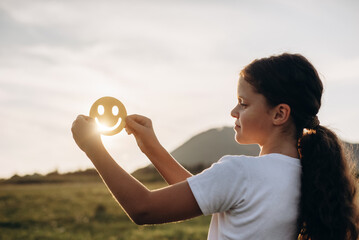 Selective focus of cute girl child holding yellow happy smile face on background amazing warm...