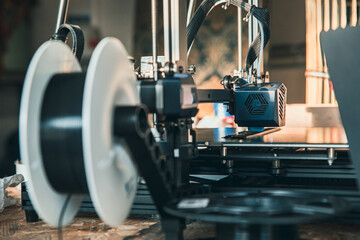 Close-up of a 3D printer head working in the rays of the setting sun. 3D printing technology in...