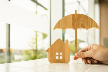 Model of umbrella with house on wooden table concept of the system of insurance savings and Housing insurance against impending loss and fire, building fire insurance concepts.