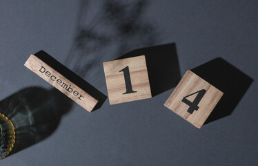 Wooden calendar with the date december 14 on a dark background with vase. Top view