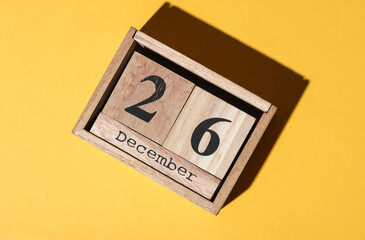 Wooden block calendar with the date december 26 on yellow background