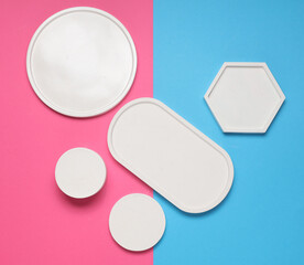 Set of Decorative white plaster trays of different shapes on blue pink background. Stands for candles organizers for cosmetics or jewelry. Top view