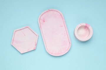Set of Decorative pink plaster trays of different shapes on a blue background. Stands for candles organizers for cosmetics or jewelry. Top view