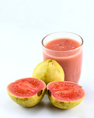 A glass of red guava juice with the fruit cut into pieces that looks fresh on a white isolated background