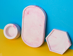 Decorative plaster trays on blue yellow background. Stands for candles, organizers for cosmetics or jewelry.