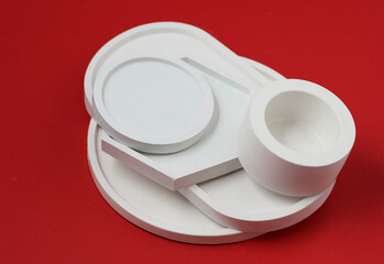 Decorative plaster trays on red background. Stands for candles, organizers for cosmetics or jewelry.