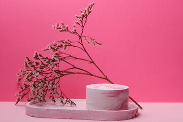 Composition of plaster figures and dried flowers on a pink background. Creative showcase, stand and podium