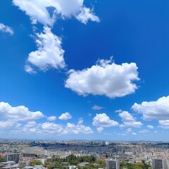 Blue sky with fluffy white clouds above city skyline.