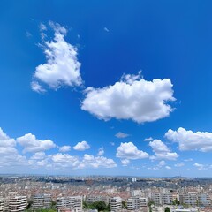 Cityscape with fluffy white clouds against a bright blue sky.