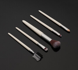 Set of white makeup brushes on a black background