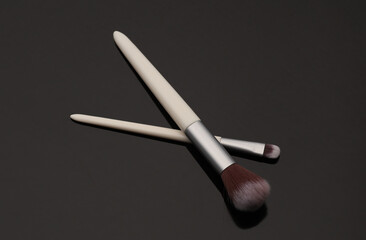 Set of white makeup brushes on a black background
