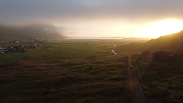 Farm buildings and fields under early morning mist and fog in Lofoten, Northern Norway by the Ryten mountain