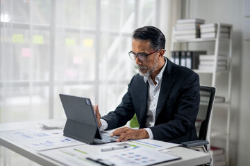 A man in a suit is working on a laptop in front of a white background