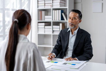 A man and a woman are sitting at a desk with papers in front of them