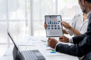 Two people are looking at a presentation with graphs on a table