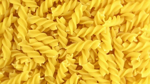 Raw spiral pasta rotates. View from above.