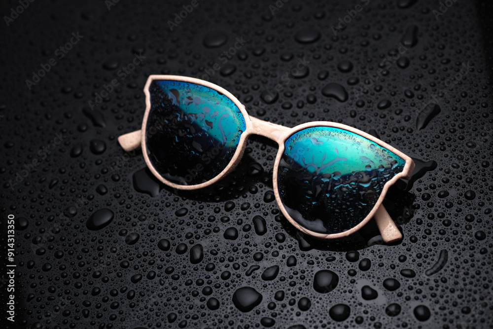 Wall mural sunglasses on a black background with water drops