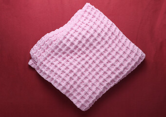 Pink knitted plaid on a red background