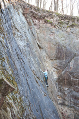 rock climber climbs an almost vertical wall of rock with a safety rope