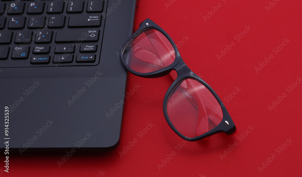 Canvas Prints Laptop with eyeglasses on red background. Top view