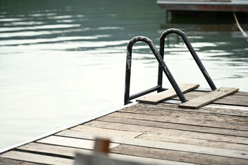 Fototapeta premium A dock ladder leads into calm lake waters, inviting swimmers for a refreshing dip in a peaceful lakeside setting
