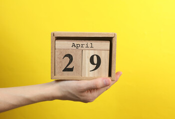 Wooden block calendar with date april 29 in hand on yellow background