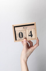 Wooden block calendar with date may 04 in hand on gray background