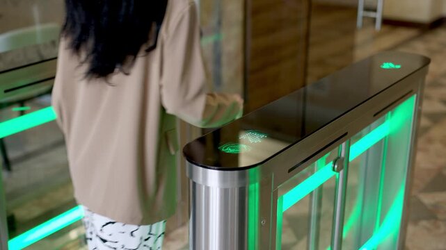 A professional businesswoman uses her personal access card to smoothly enter her workplace through a modern turnstile in a stylish office lobby. Perfect for themes of office security, efficiency, and 
