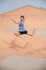 Dancer is gracefully leaping in the air, showcasing his talent and athleticism against an urban backdrop