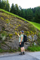 Obraz premium A passionate middle aged woman takes pictures of alpine meadows on her phone. She holds a gimbal in her hands. The lady blogs about her travels on social networks. Hohe Tauern . Austria