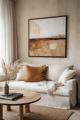 Cozy living room with neutral tones, featuring a white sofa, abstract wall art, and natural decor elements like dried flowers.
