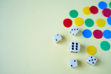 White dices and colorful tokens on yellow background.