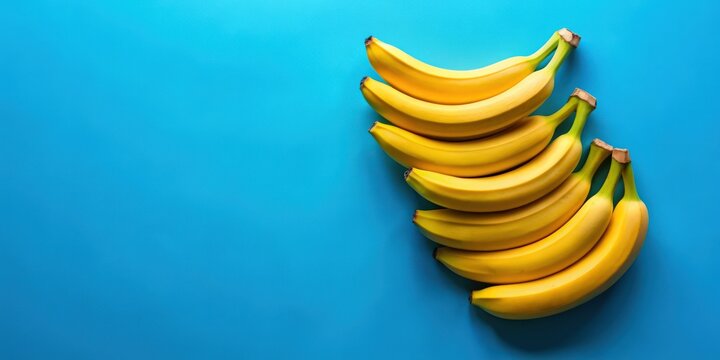 Fresh bananas arranged neatly on a vibrant blue background, bananas, fruit, fresh, ripe, yellow, healthy, snack, tropical