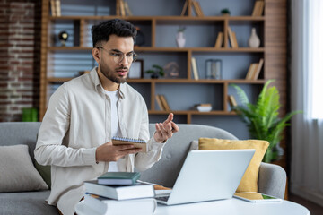 Young man studying remotely online from home using laptop during video call with mentor