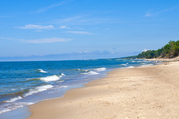 Obraz premium Empty, sandy beach and sea waves by sunny day