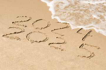Inscription 2024 and 2025 numbers written on sand.  New Year 2025 replace 2024. Concept on the sea...
