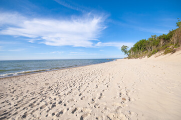 Empty, sandy beach and sea waves by sunny day