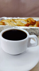 Cup of coffee in a traditional brazilian breakfast countaining bread on the background
