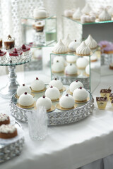 A buffet table with dessert cakes on a glass stand.